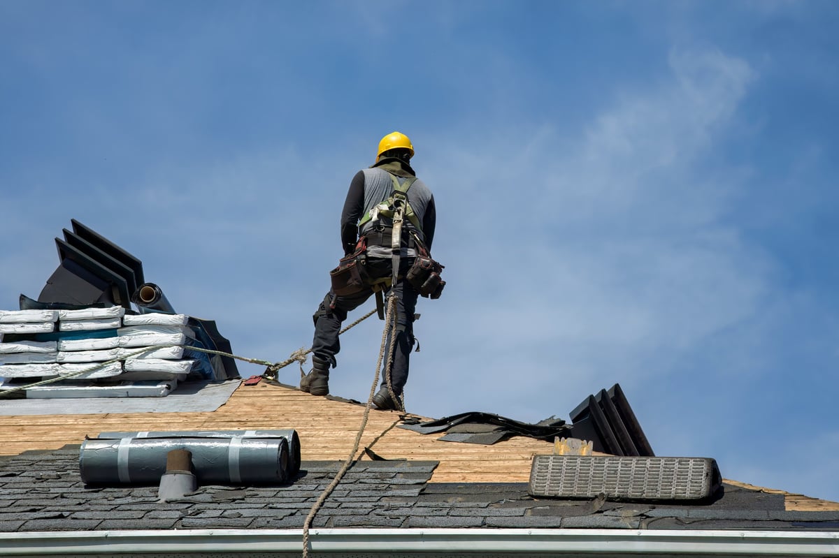 Construction worker using pneumatic nailer on roof